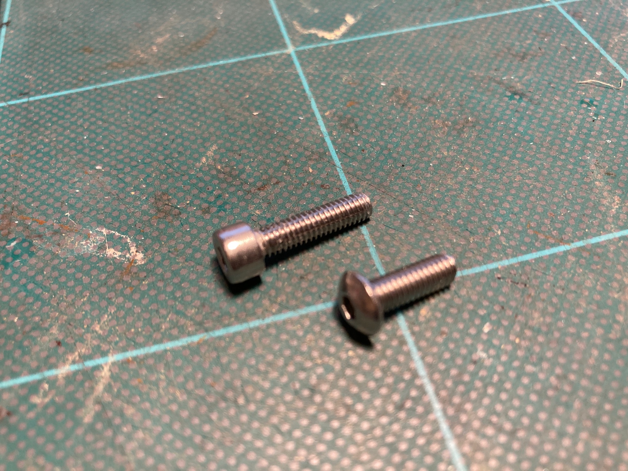 New button head screw alongside longer cap head screw.