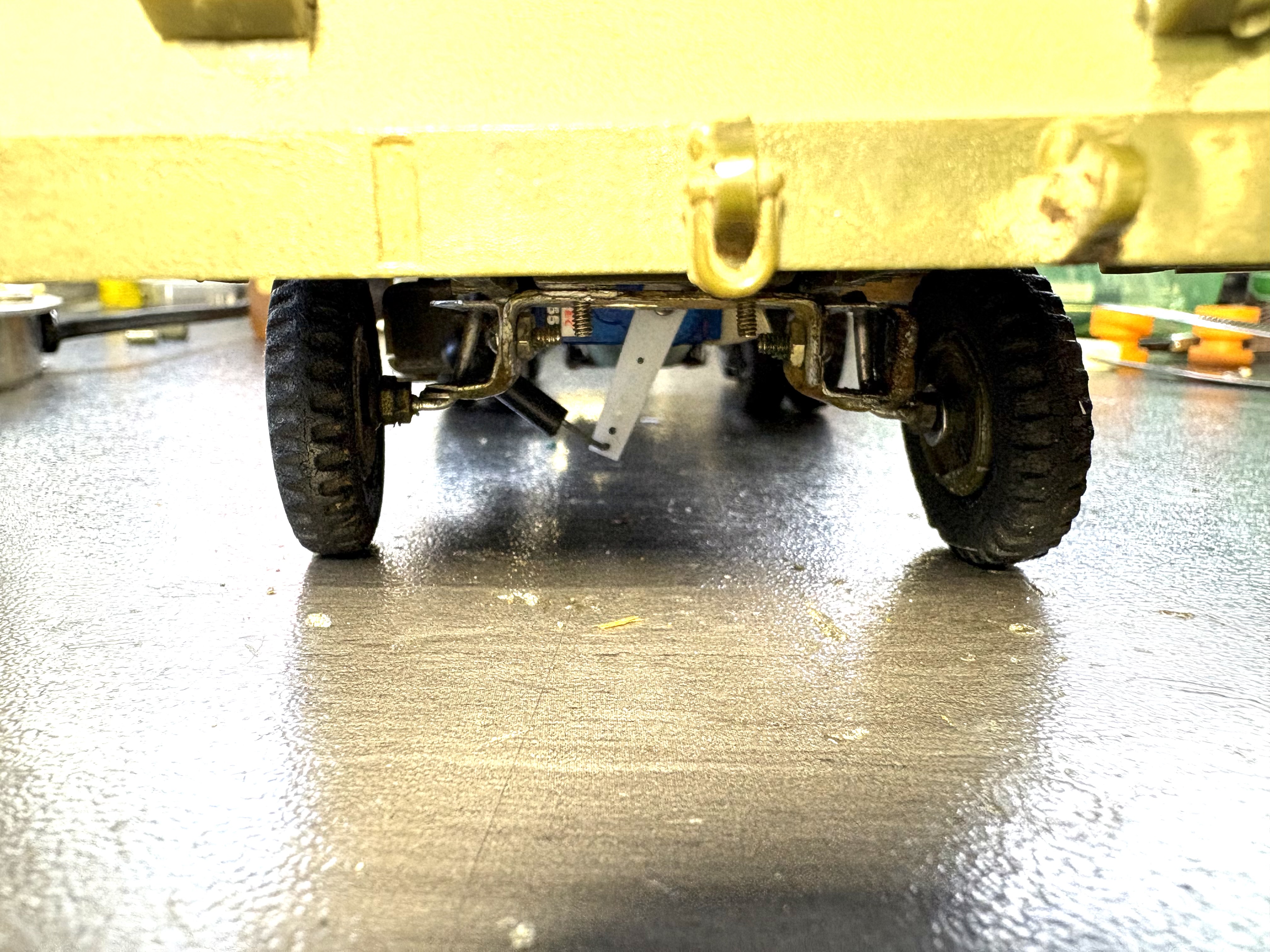 This is a view of the hand made metal front end under this M-26. I used to run this truck outside back when I lived in Tucson AZ. To run there, I needed a 4WD rear dually axle with wider front tires. I just changed the rims today to the stock width military front wheels as I no longer run it outside. In the video you can see the older white front rims inner rim extensions as the truck is coming towards the camera. Those extenders have been removed and are now back to stock width as seen in the first picture above. Yes that is an extra long servo horn to give me a tight turning radius as required for my indoor track.