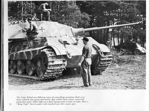 King Tiger being painted by two crewmen in a field with spray gun. Third crewmen activities undetermined.
