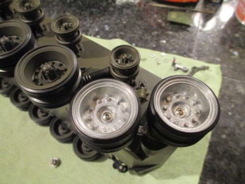 Installed metal suspensions and idlers and road wheels with bearings.  These came with the caps, one of which can be blurrily made out sitting by the hull on the green cloth.